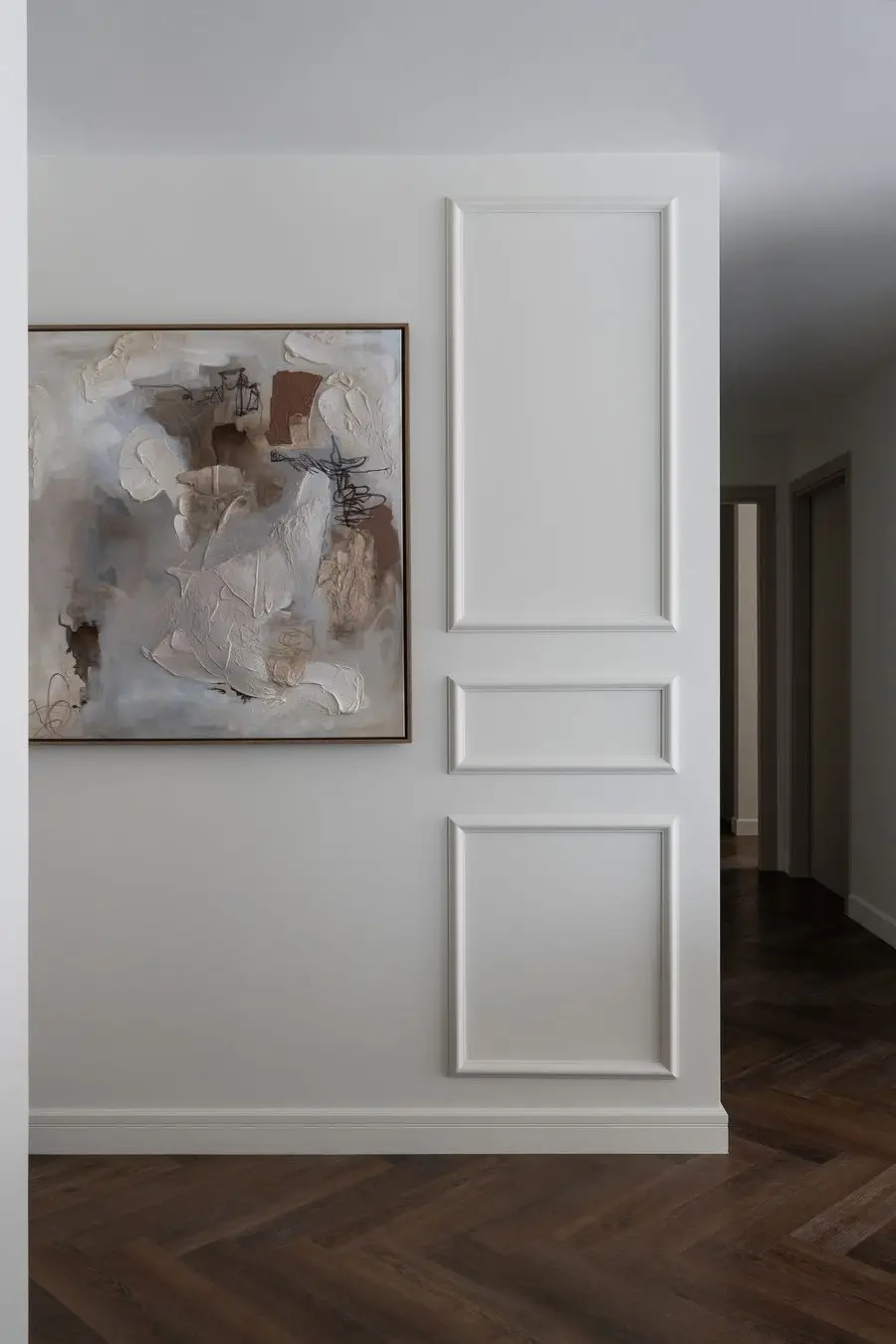 Hall with wall mouldings, abstract art and a herringbone floor