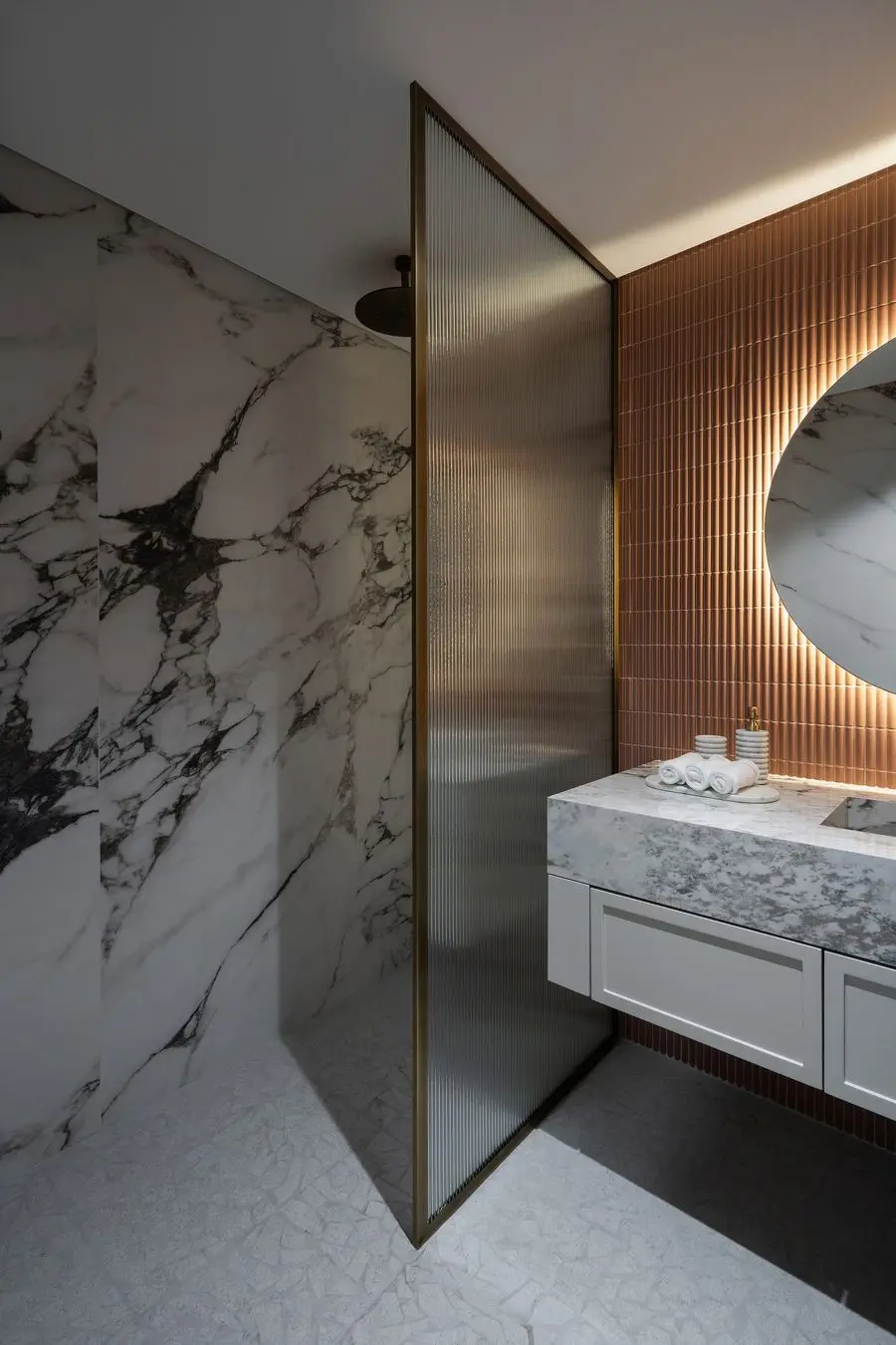 Veined stone wall with a fluted glass screen and brass profile