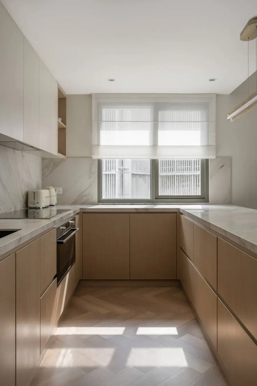 Light oak kitchen run with a veined splashback under a window