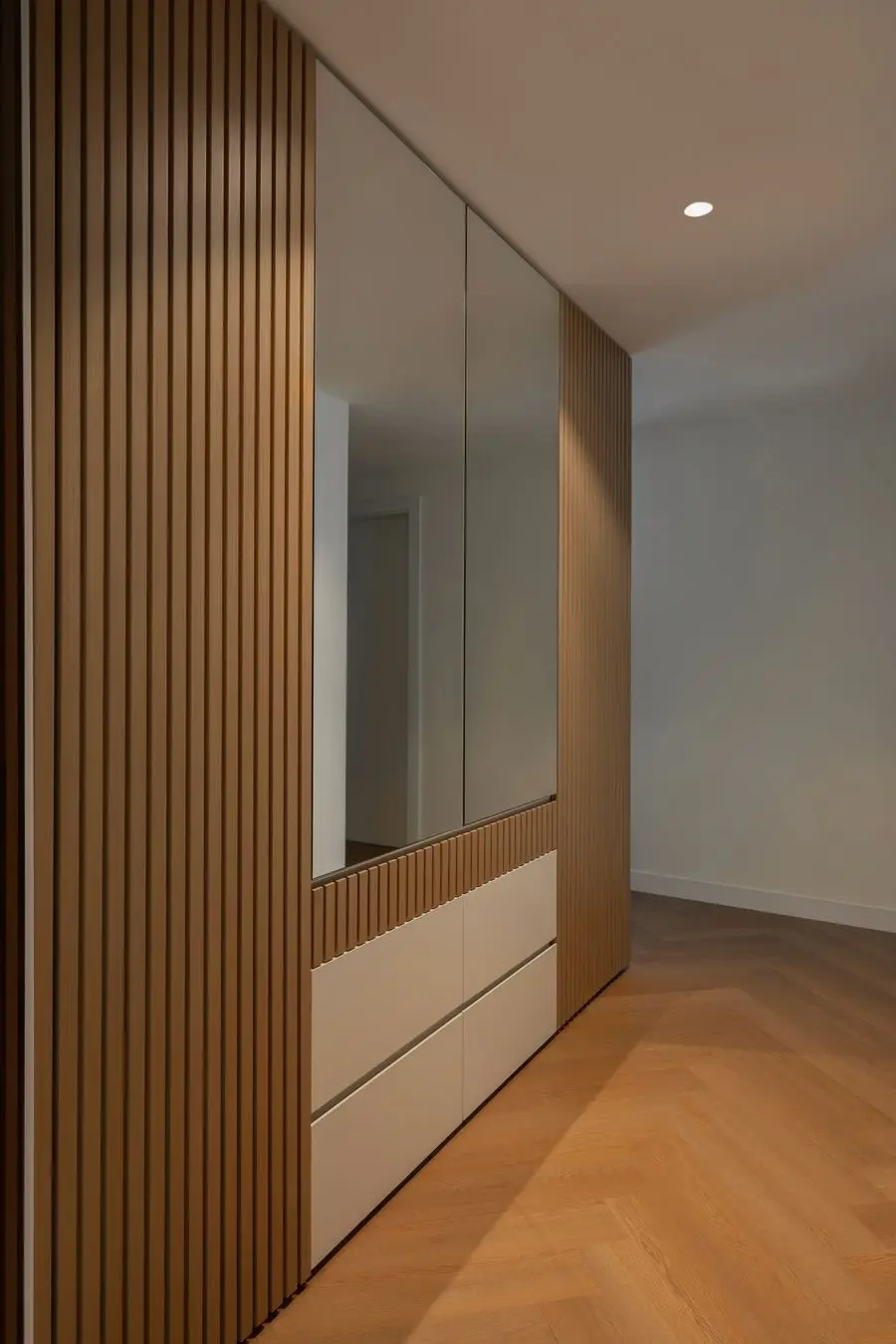Slatted wood wardrobe with mirrored doors over a herringbone floor