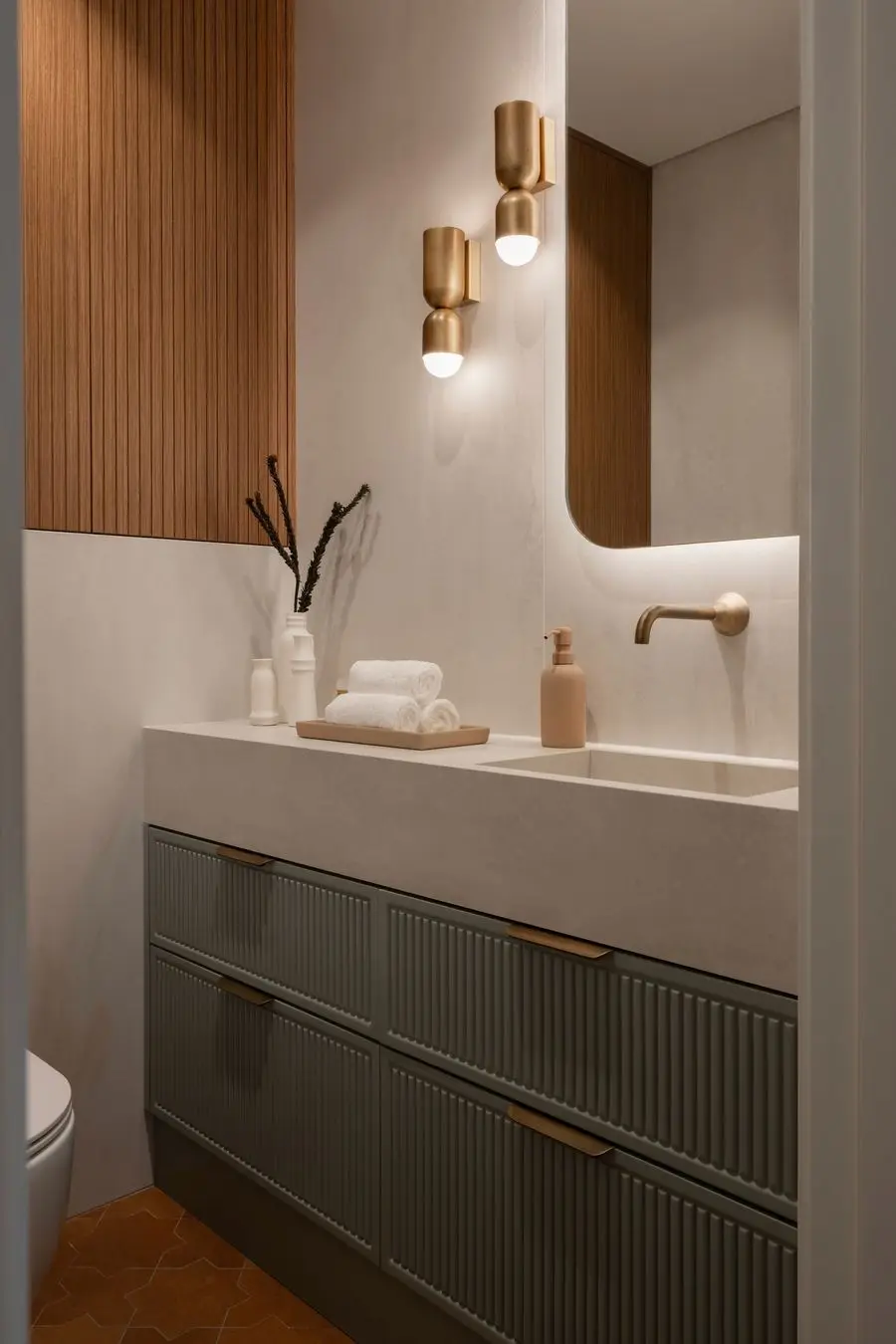 Powder room with a sage fluted vanity and brass sconces