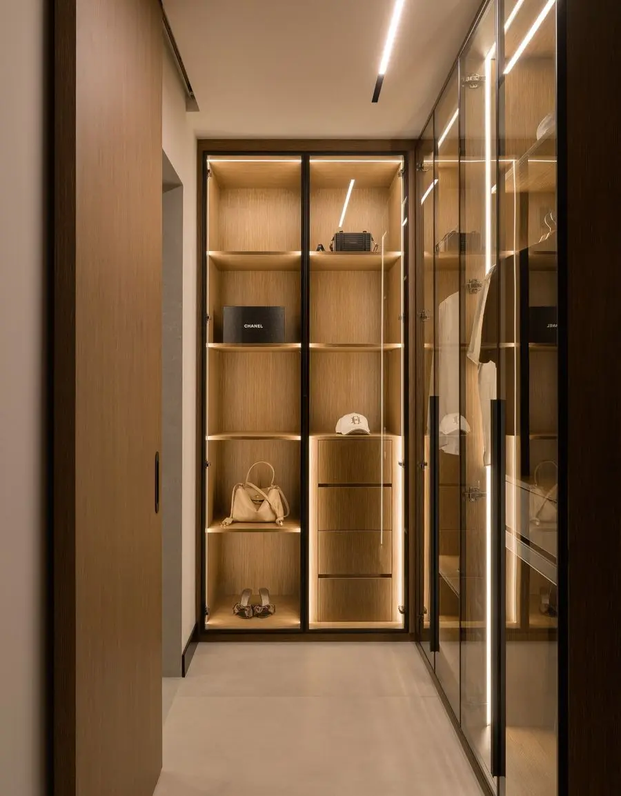 Walk-in wardrobe with black-framed glass and backlit shelving