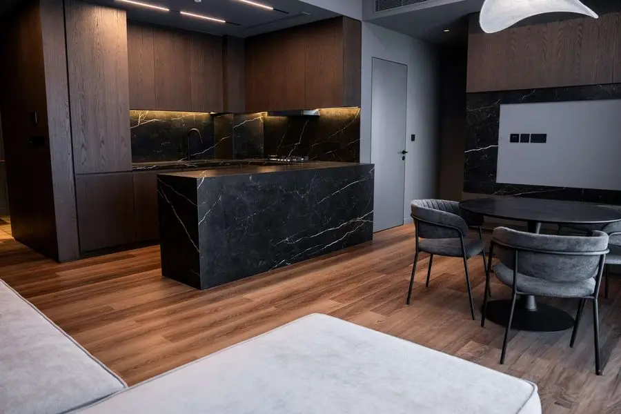 Open-plan living with a black veined stone island and dining set
