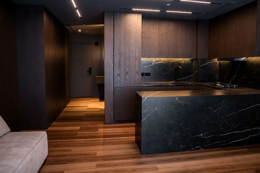 Dark kitchen with a black stone island seen from the sofa