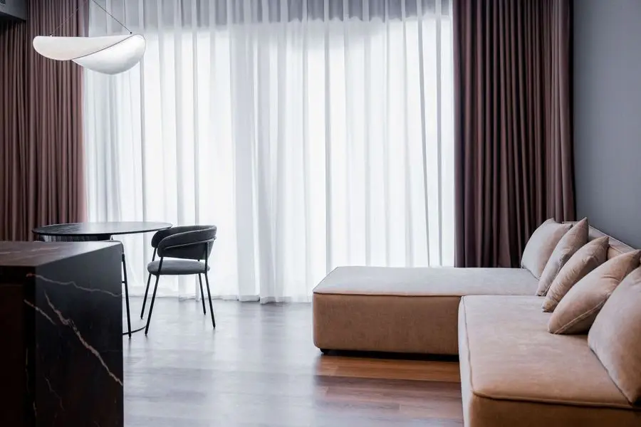 Living area with a low sofa and full-height sheer curtains