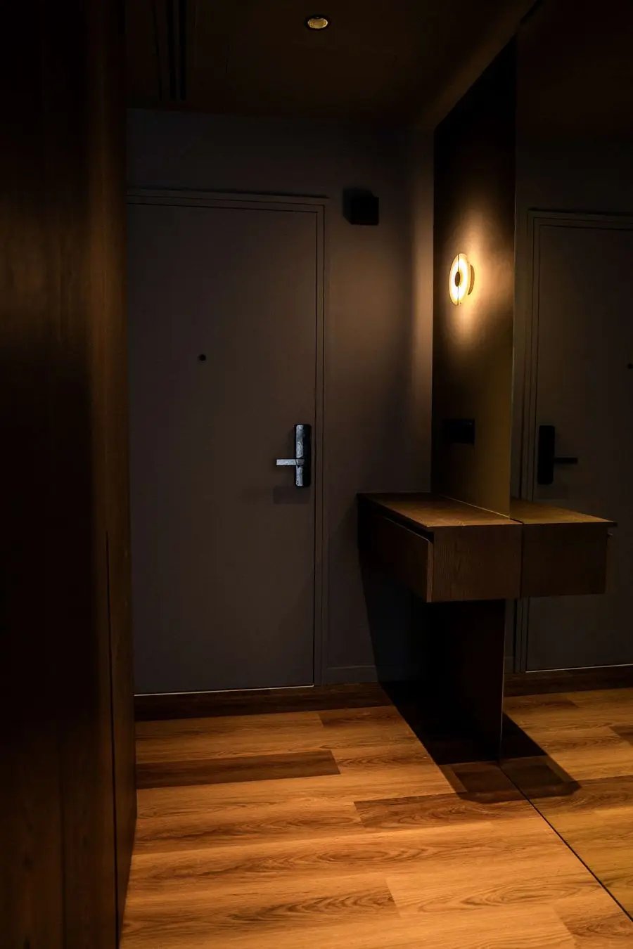 Entry with a dark wood door, console and wall sconce