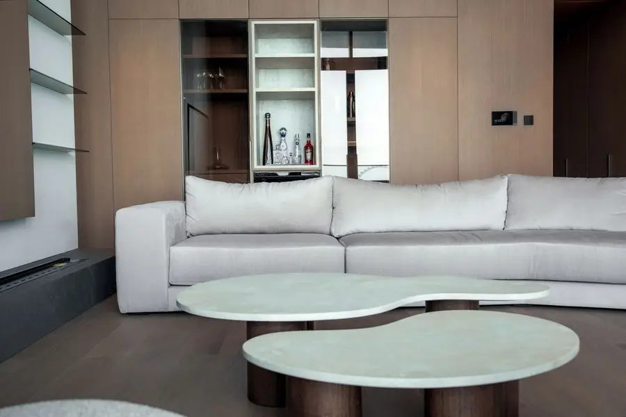 Living room with sculptural stone coffee tables, a white sofa and oak joinery