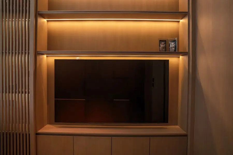 Backlit TV niche framed by slatted oak panelling