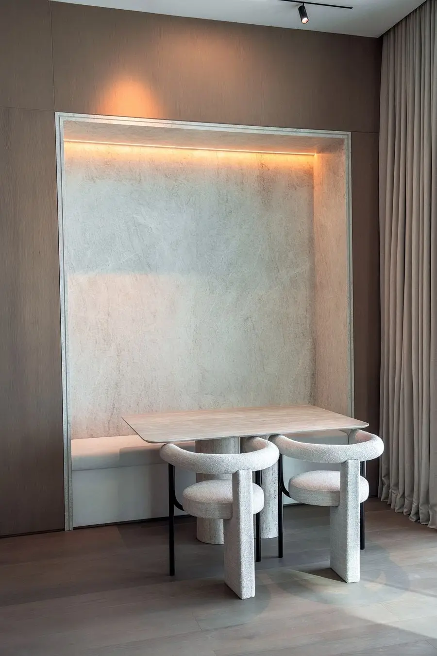 Dining nook with a backlit niche and bouclé chairs