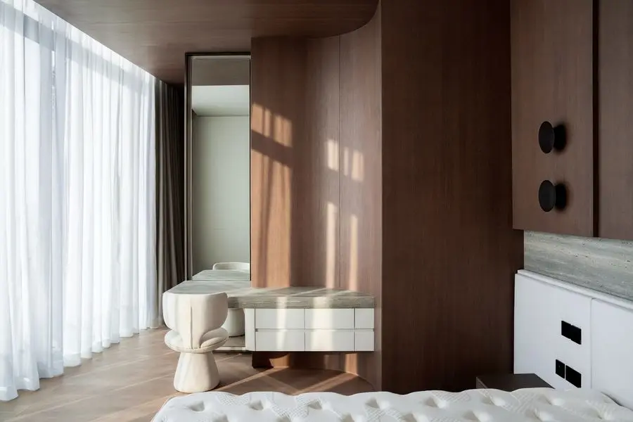 Bedroom with a curved walnut wall and sheer curtains