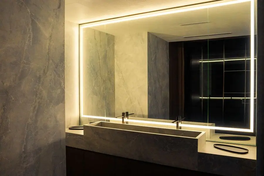 Bathroom with a backlit mirror over a stone basin