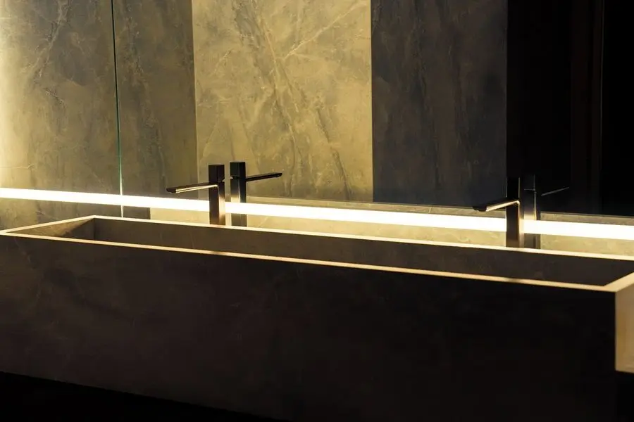 Dark stone trough basin with a backlit mirror edge