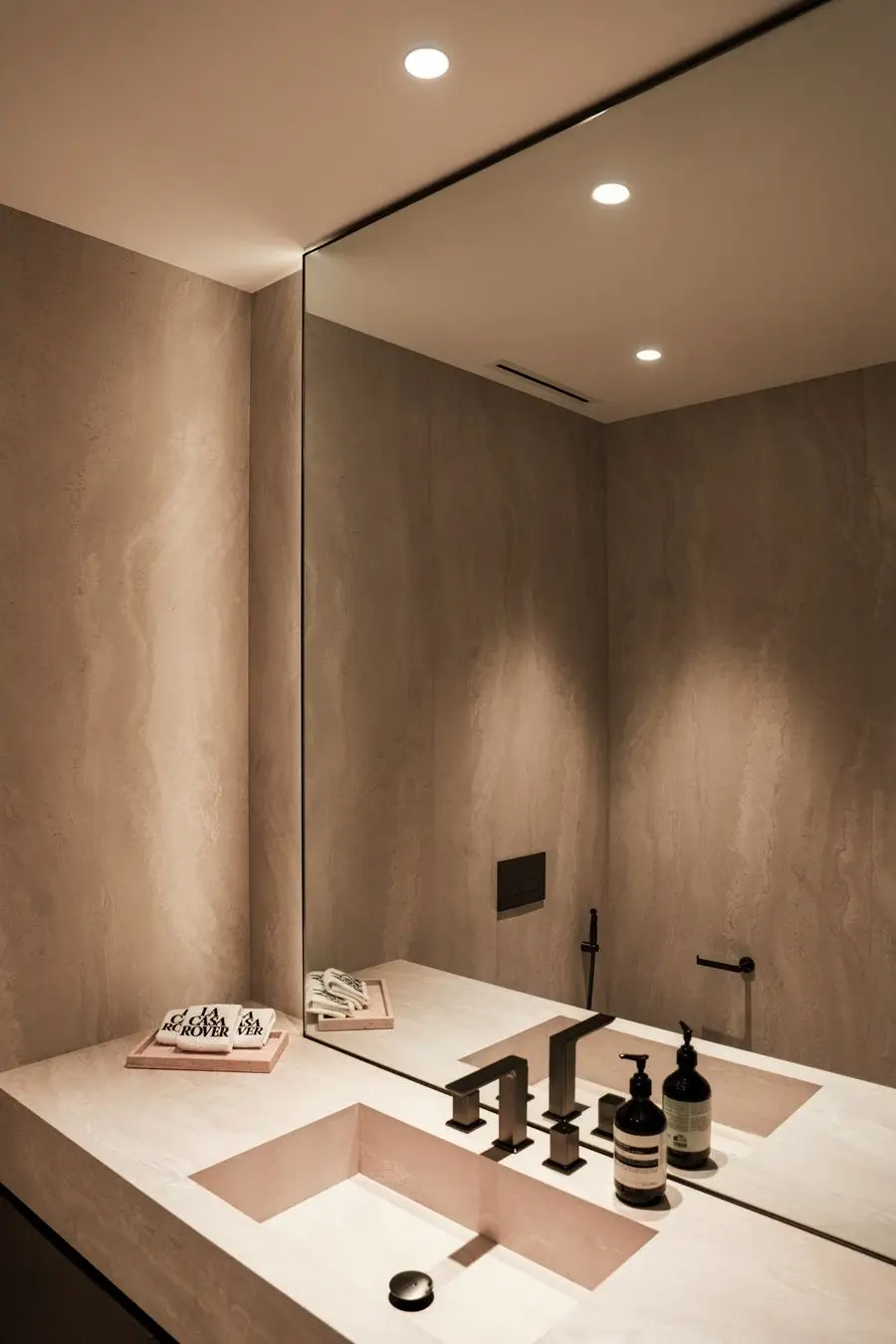 Powder room with a blush stone basin and a wall-to-wall mirror