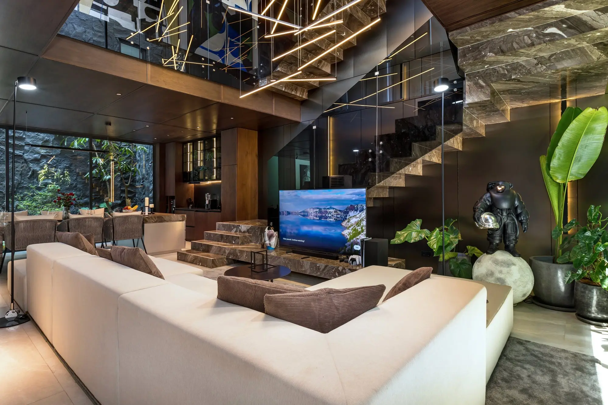 Double-height living room with a suspended LED light sculpture and a marble stair