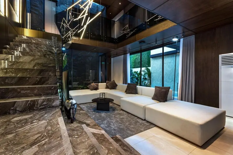 White sectional under a veined marble stair with glass balustrade
