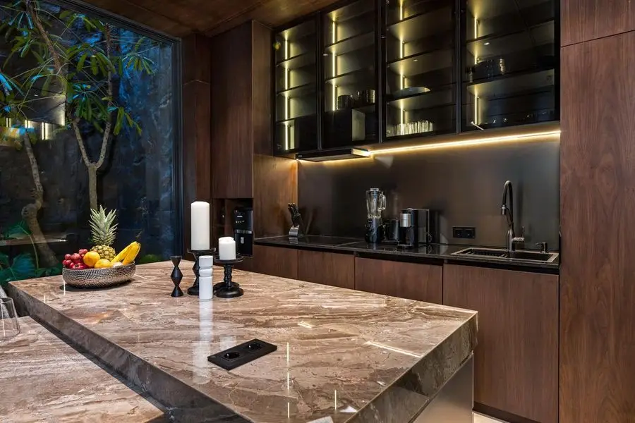 Kitchen with a veined stone island and backlit black-glass cabinets