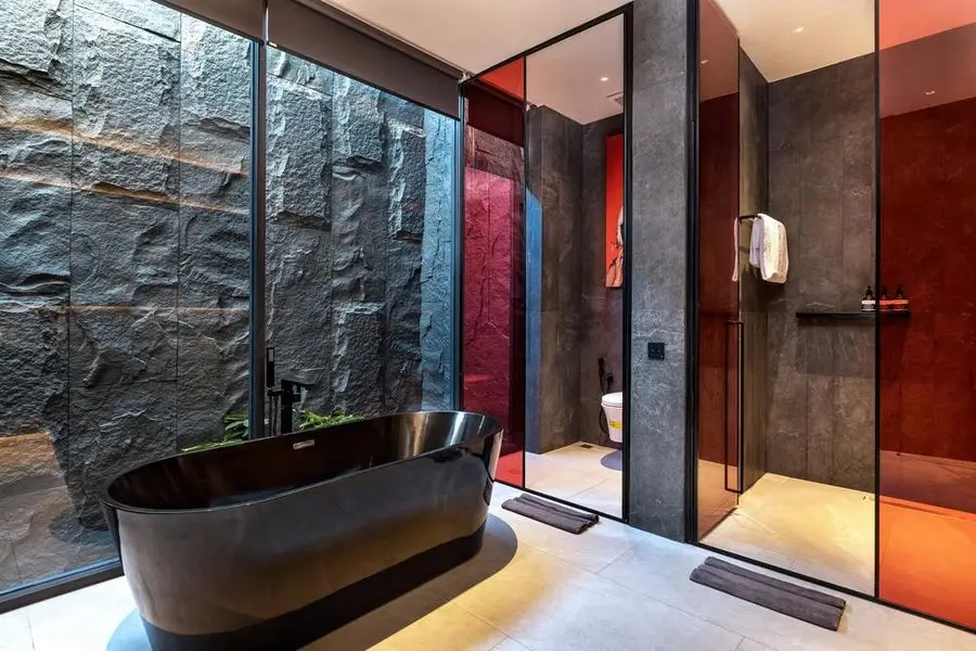 Main bathroom with a freestanding black tub against a rough stone wall
