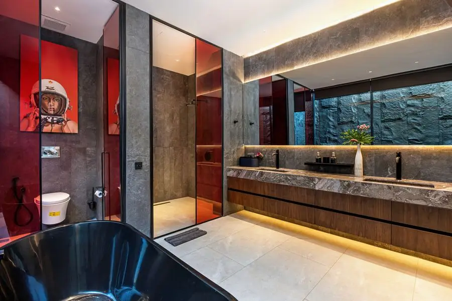 Main bathroom with a stone vanity, red glass and a freestanding tub
