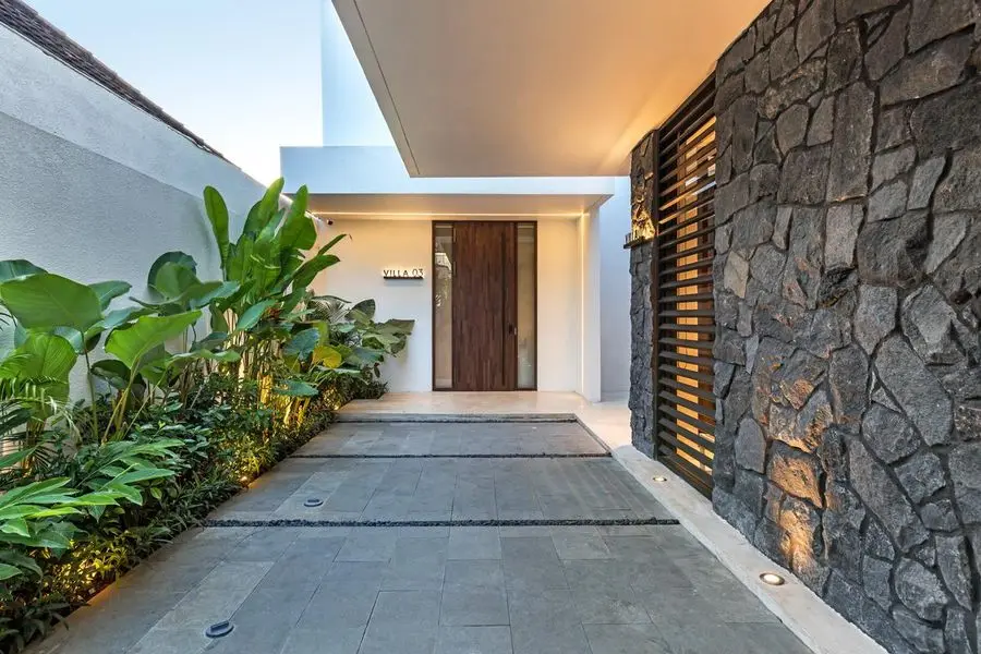 Entrance path along a dark stone wall with planting