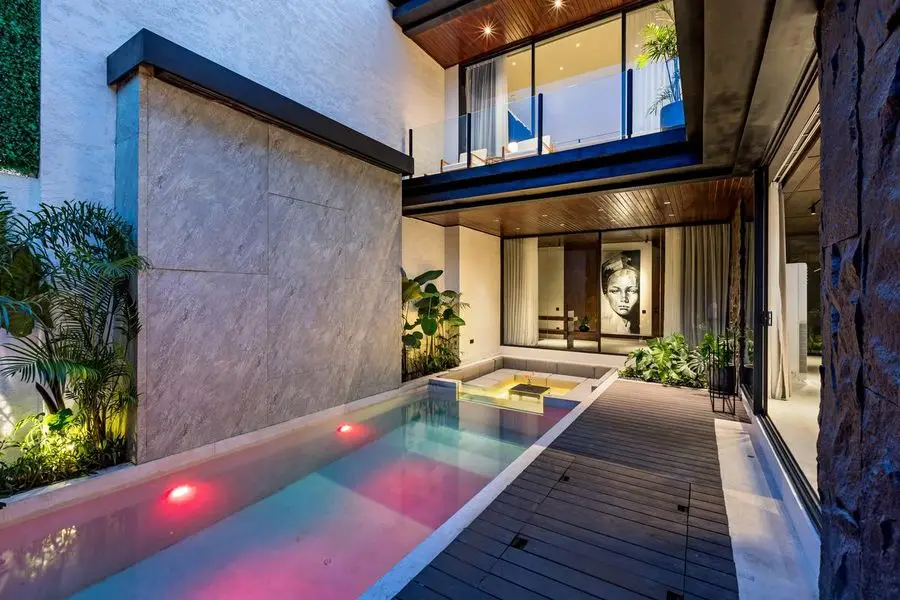 Pool terrace beside the glazed living room at dusk