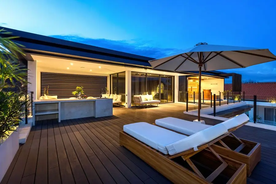 Rooftop terrace with loungers, umbrella and a bar counter at blue hour