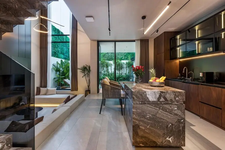 Kitchen with a veined stone island, walnut units and a garden view