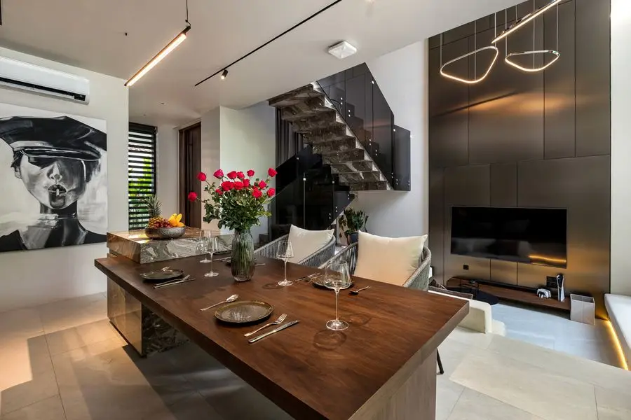 Walnut dining table under the marble stair, with portrait art