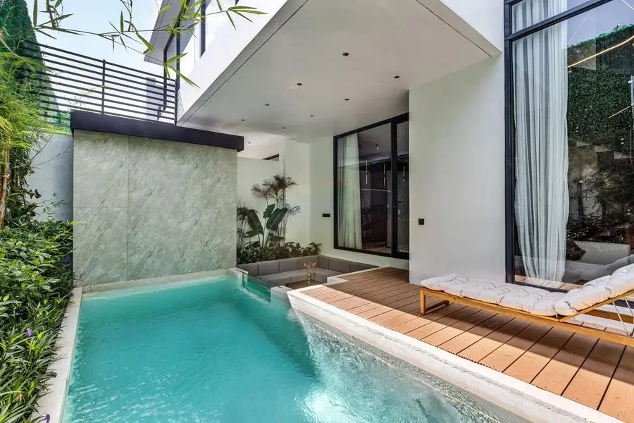 Pool with loungers on a timber deck beside the living room glass