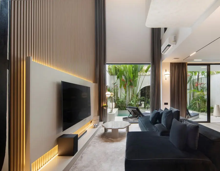 Living room with a slatted timber TV wall opening to the pool courtyard