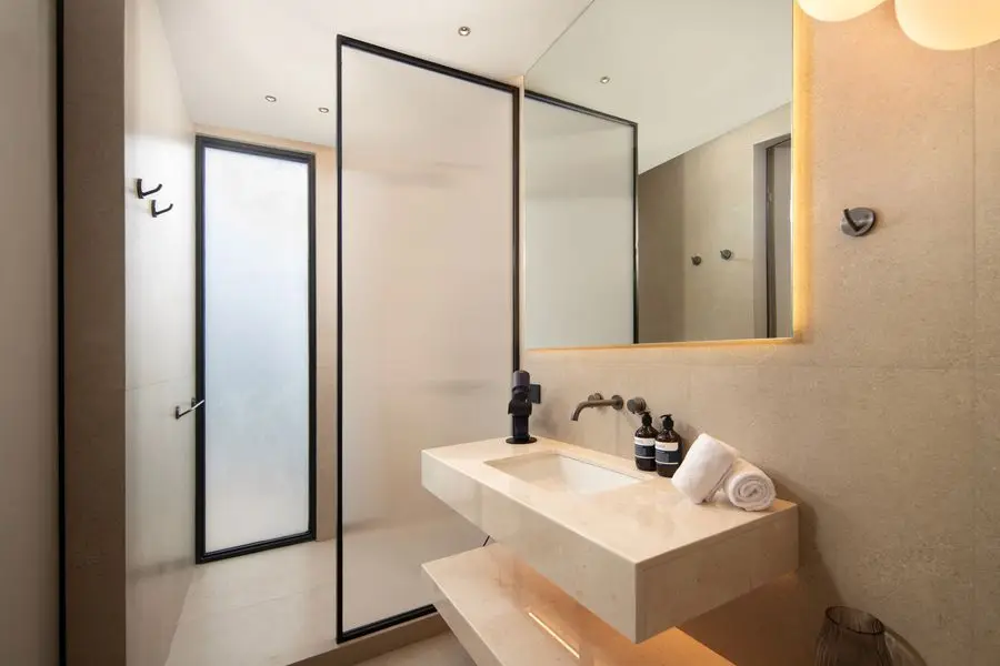 Bathroom with a floating stone vanity, black fittings and a glass shower