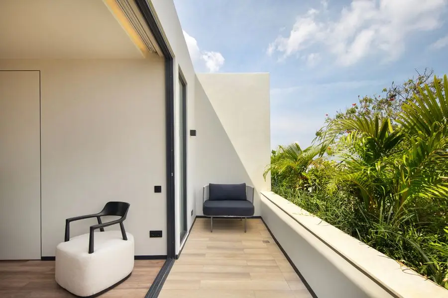 Upper terrace with a white armchair looking over lush greenery