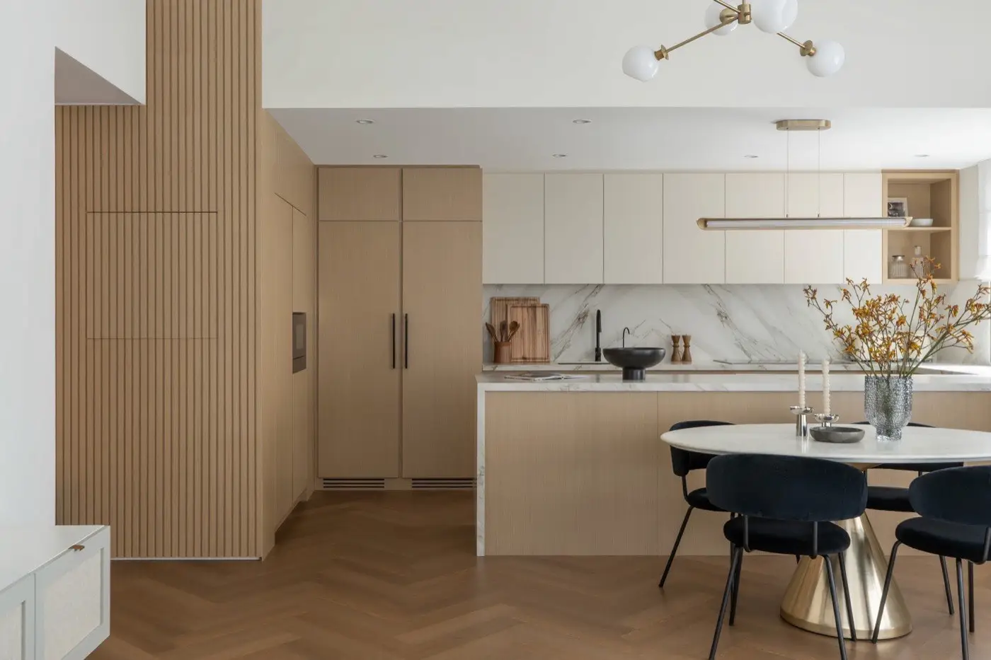 Light oak kitchen with a herringbone floor and a round dining table