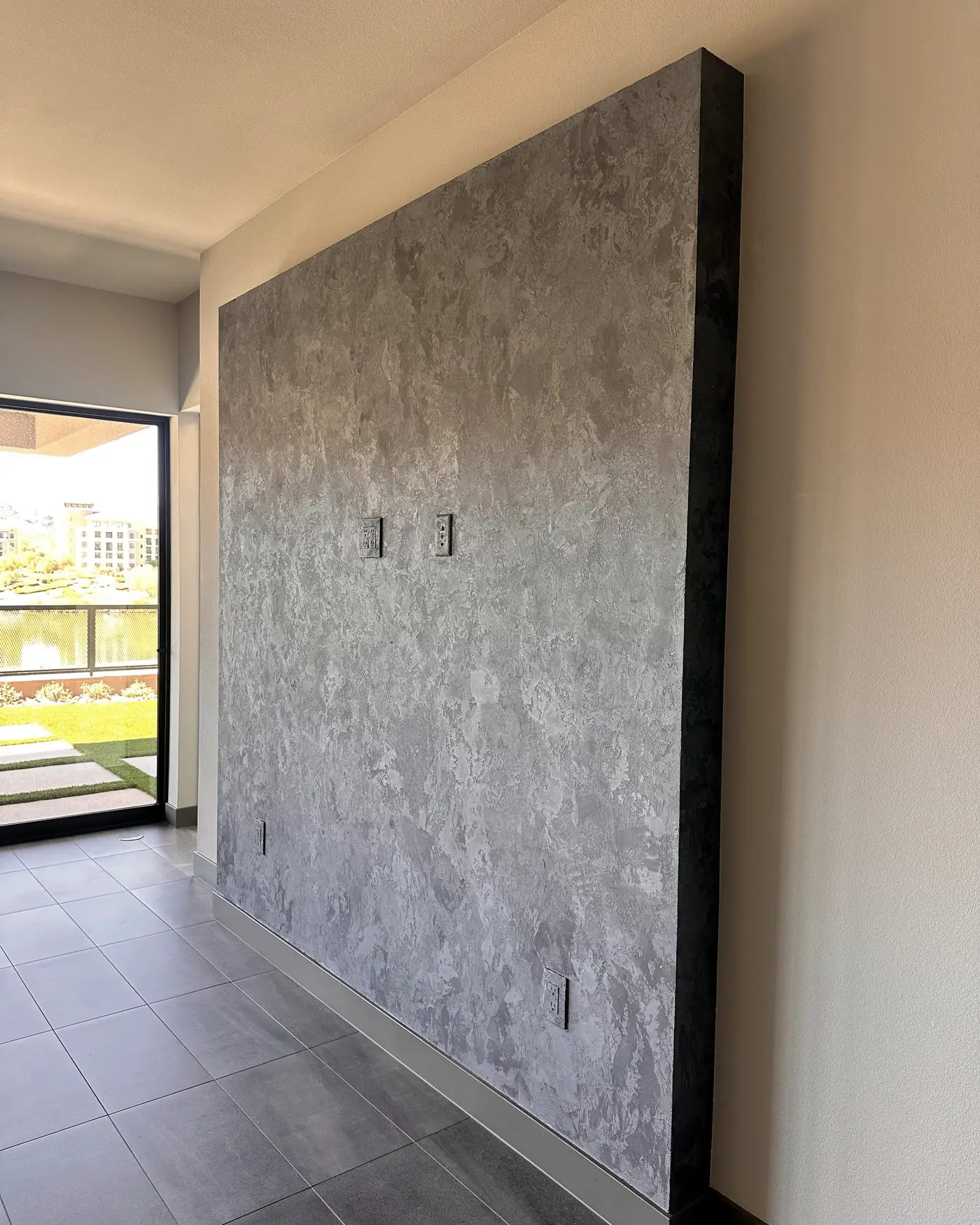 Pared protagonista independiente en estuco mineral Velvet gris en una sala luminosa, trabajo de nuestros maestros
