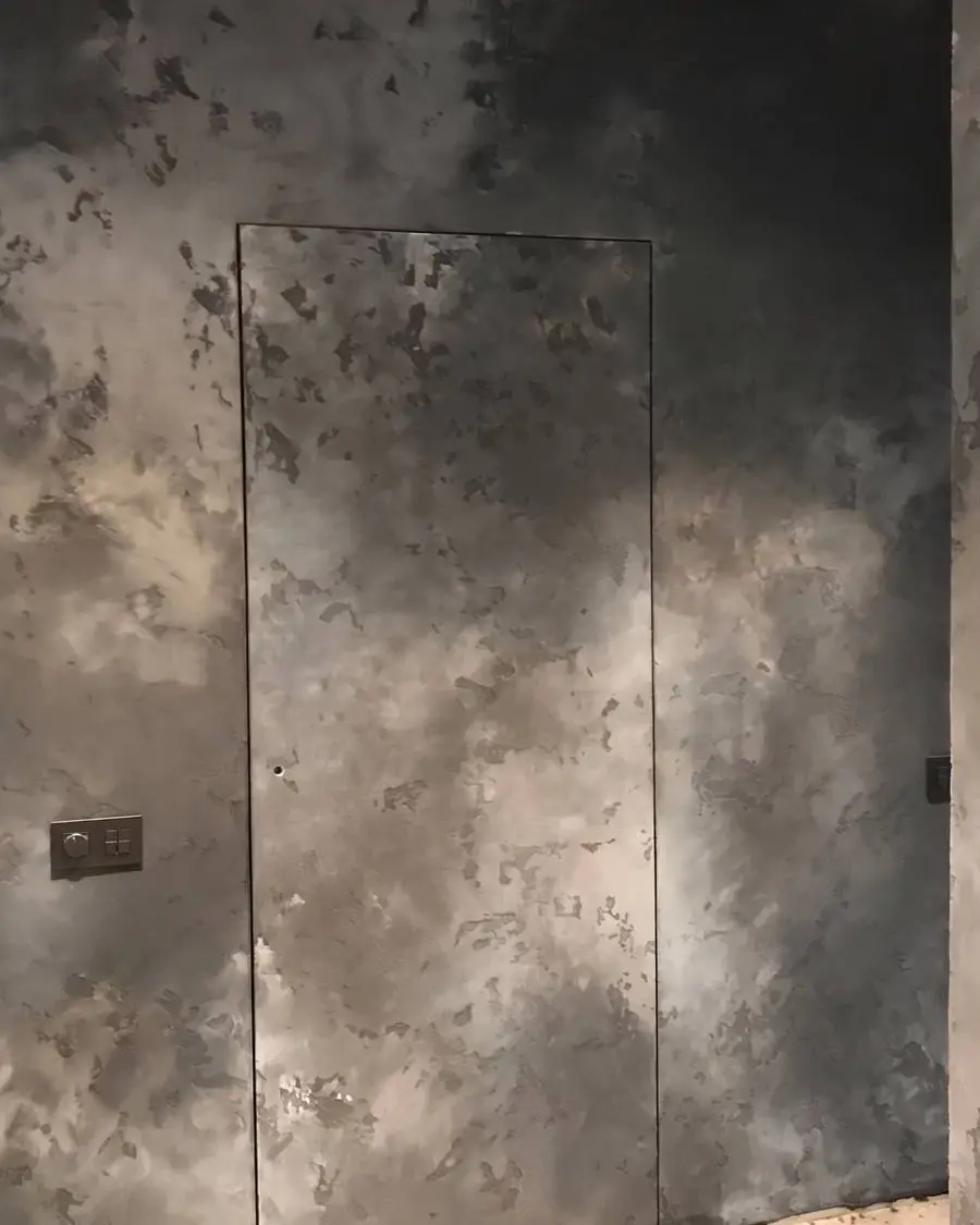 Puerta oculta a ras en una pared de estuco mineral gris humo